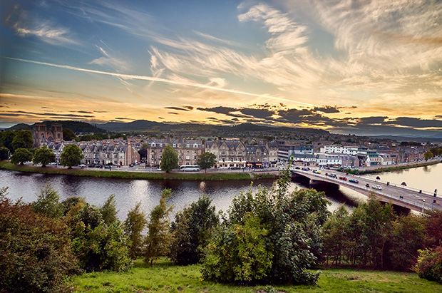 Landscape photograph showing a river running through a city at sunset.