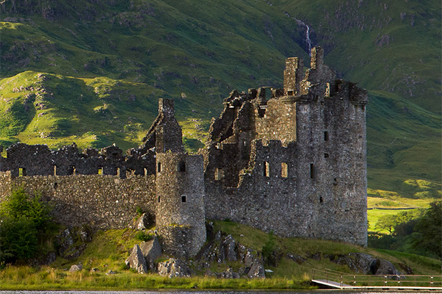 A medieval Scottish castle ruin surrounded by green hillside.