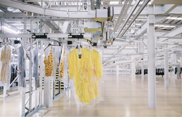 A yellow dress hangs on an automated clothing rail in a factory.