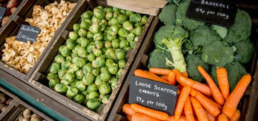 A selection of fresh vegetables, including carrots, broccoli and sprouts for sale in a greengrocers