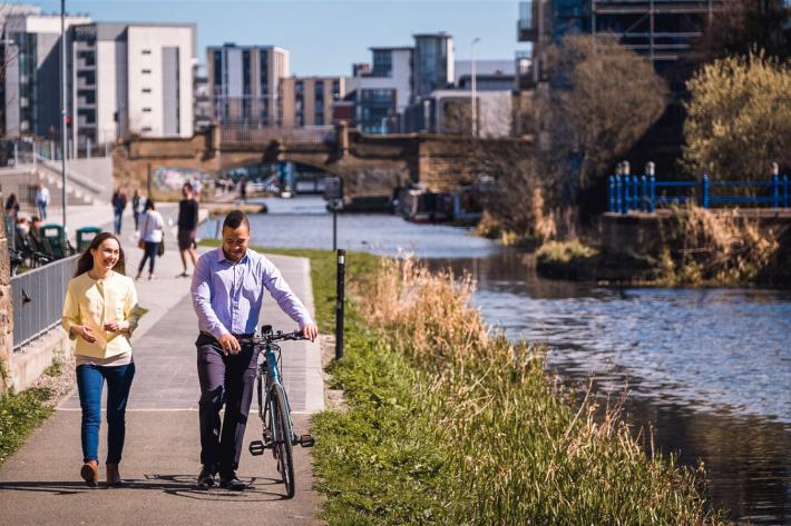 Two people walking along with a bike, next to Edinburgh's Union Canal