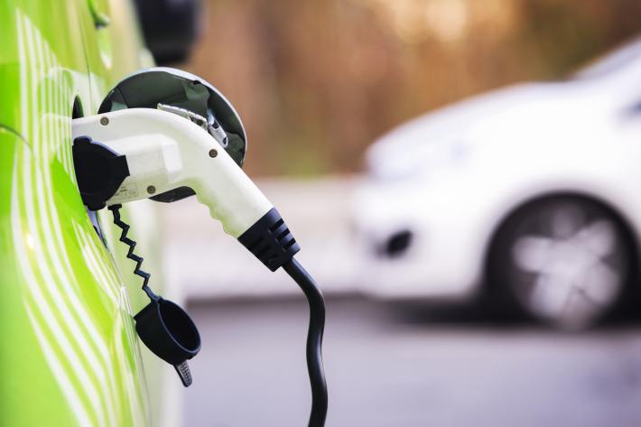 Close up of a white plug charging a green electric car