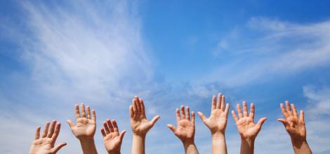 hands in the air in front of a blue sky